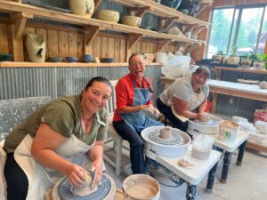 Three people taking a pottery lesson